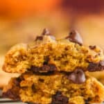 a pumpkin chocolate chip cookie that has been broken in half and stacked one on top of the other