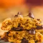 a pumpkin chocolate chip cookie that has been broken in half and stacked one on top of the other