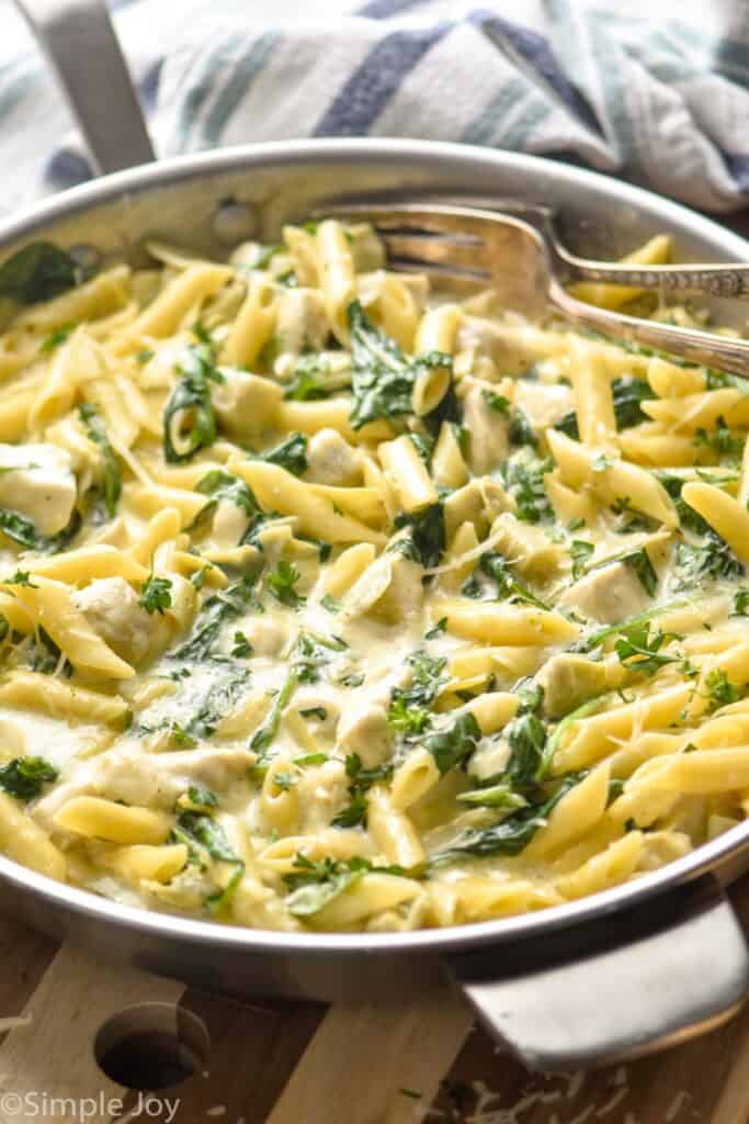 side view of a skillet full of spinach artichoke pasta recipe