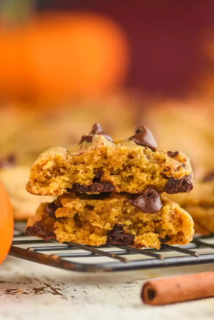 a pumpkin chocolate chip cookie that has been broken in half and stacked one on top of the other
