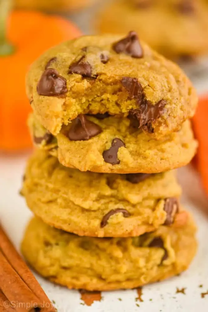 a small stack of pumpkin chocolate chip cookies with a bite missing on top