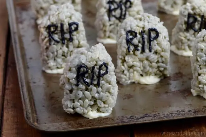 On a baking sheet, the Rice Krispies are in the shape of stone hedges in a grey color with the words RIP and stuck on the sheet pan by frosting. 