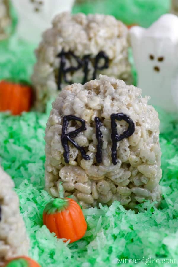 The Rice Krispies Treat Graveyard has a grey tint to it, shaped like a rounded top hedge stone, written on it with capital black letters RIP, and on top of green tinted coconut flakes. 