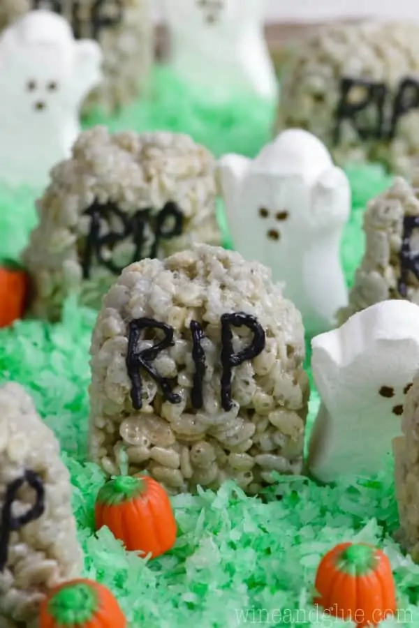 The Rice Krispies Treat Graveyard has a grey tint to it, shaped like a rounded top hedge stone, written on it with capital black letters RIP, and on top of green tinted coconut flakes. 