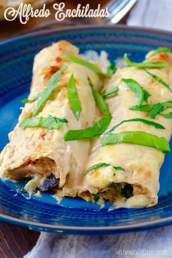 On a blue plate, the Alfredo Enchiladas have cheese oozing out and topped with spinach. 