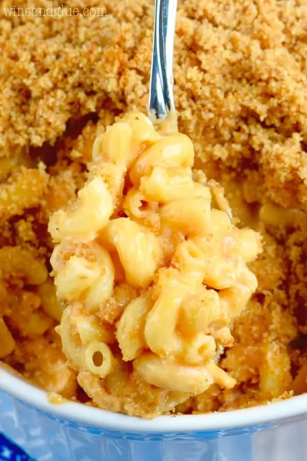 A spoon dug up some of the BBQ Chicken Macaroni and Cheese is creamy sprinkled with breadcrumbs. 