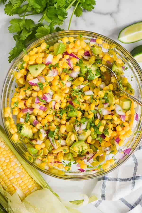 An overhead photo of the Best Corn Salsa has corn, avocado chunks, minced red onions, minced jalapeños, and cilantro mixed in. 