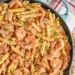 one pot creamy shrimp pasta in a skillet, garnished with parmesan and parsley