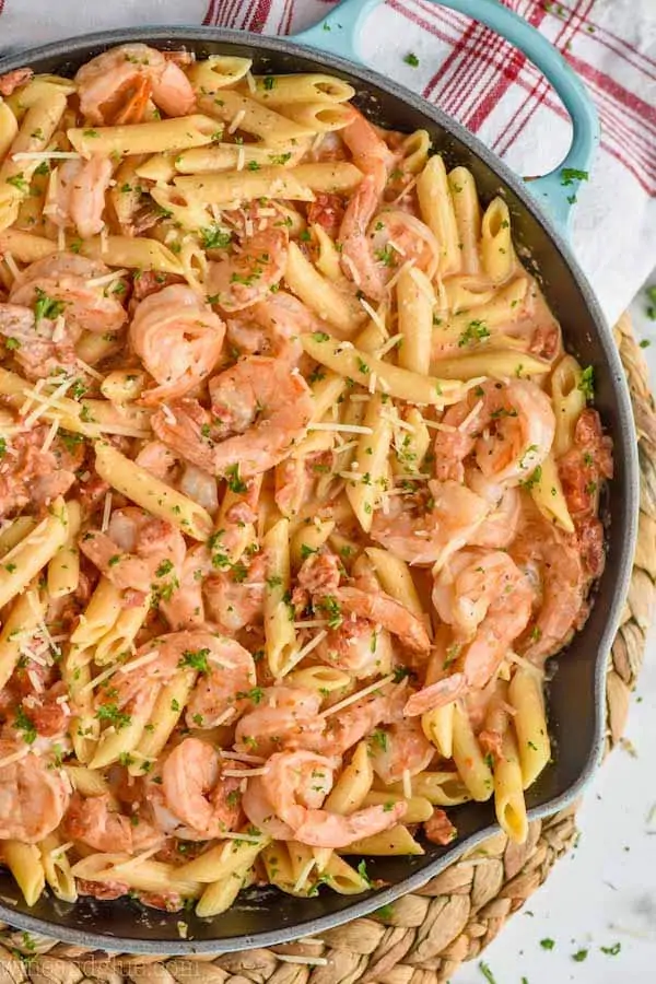 one pot creamy shrimp pasta in a skillet, garnished with parmesan and parsley