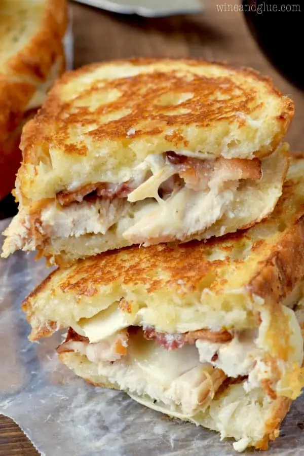 A stack of the Turkey Bacon Brie Grilled Cheese Sandwich are cut in half showing the melted gooey center. 