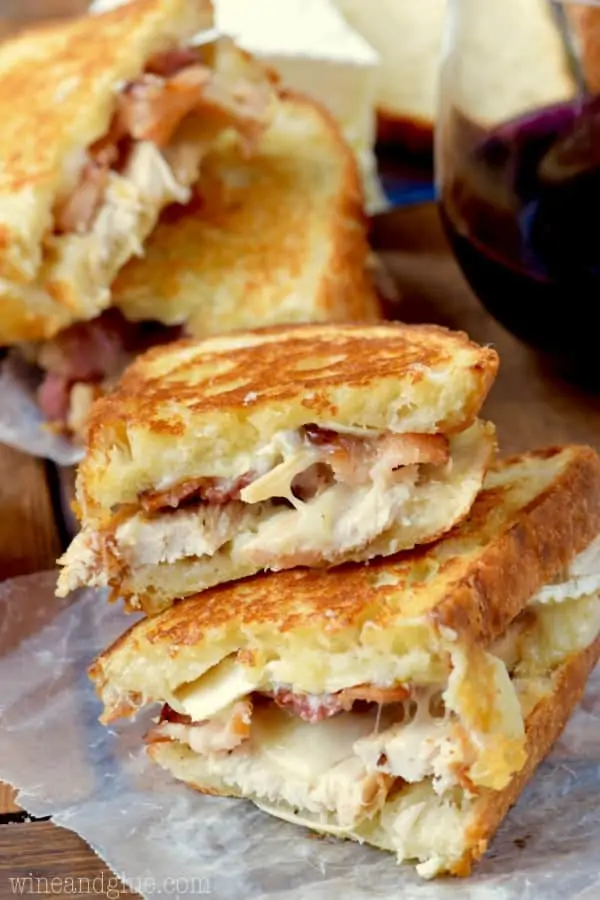 A stack of the Turkey Bacon Brie Grilled Cheese Sandwich are cut in half showing the melted gooey center. 