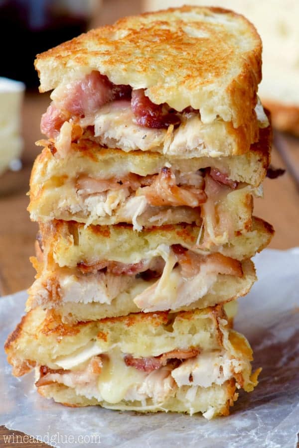 A stack of the Turkey Bacon Brie Grilled Cheese Sandwich are cut in half showing the melted gooey center. 