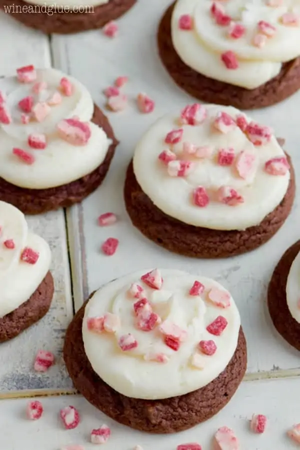 On a white counter the Chocolate Peppermint Cake Mix Cookies have white frosting sprinkled with broken pieces of peppermint. 