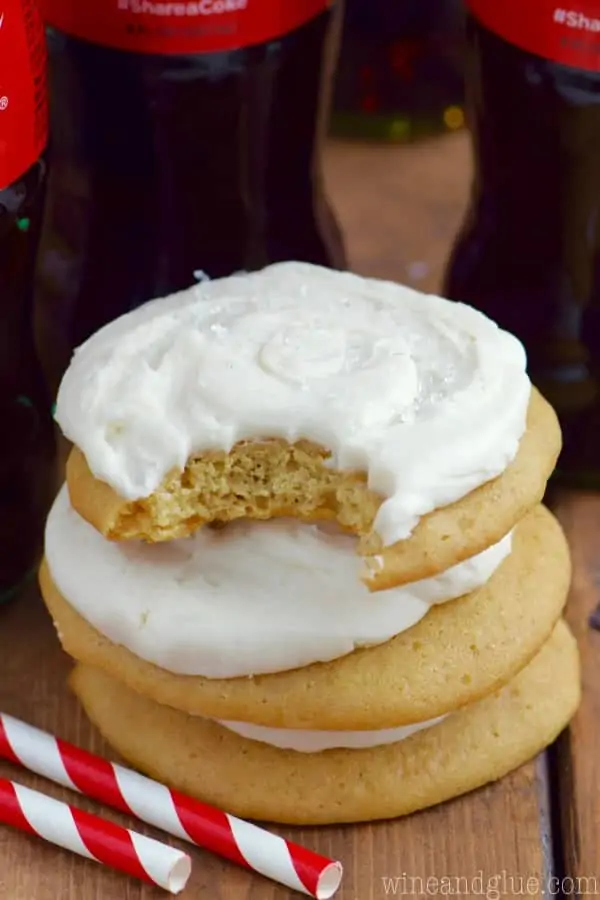 In a stack, the Coca-Cola Cookies have a darker brown color with white Coca-Cola frosting 