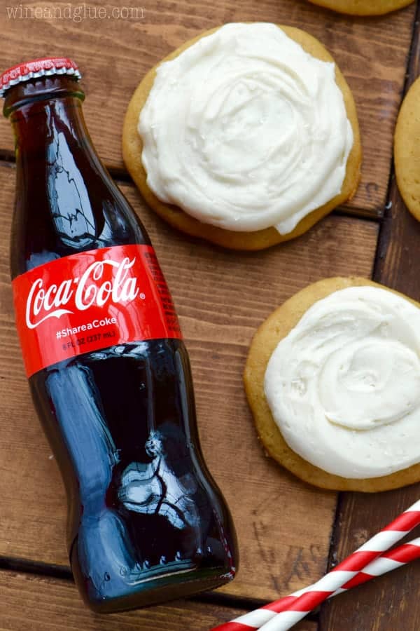 On its side, a glass Coca-Cola bottle is right next to two Coca-Cola Cookies. 