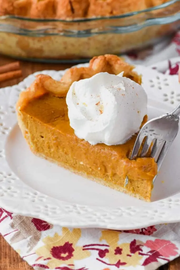 fork digging into a slice of the best pumpkin pie with a dollop of whipped cream
