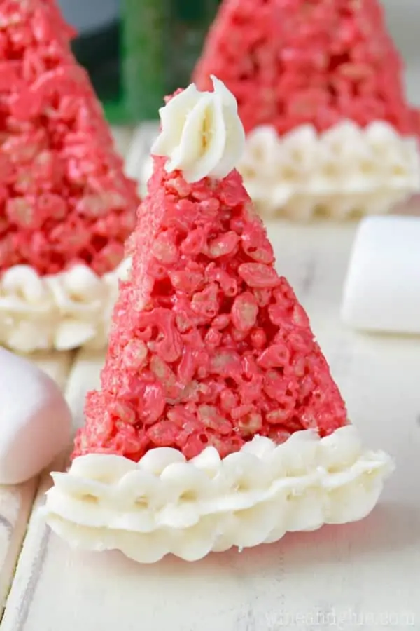 In a triangle shape, the Rice Krispies are dyed a bright red color with frosting on the tip and at the bottom making it look like a Santa's Hat