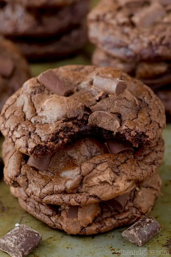 A stack of the Triple Chocolate Chunk Cookies with large chocolate chunks on top and a fluffy interior. 