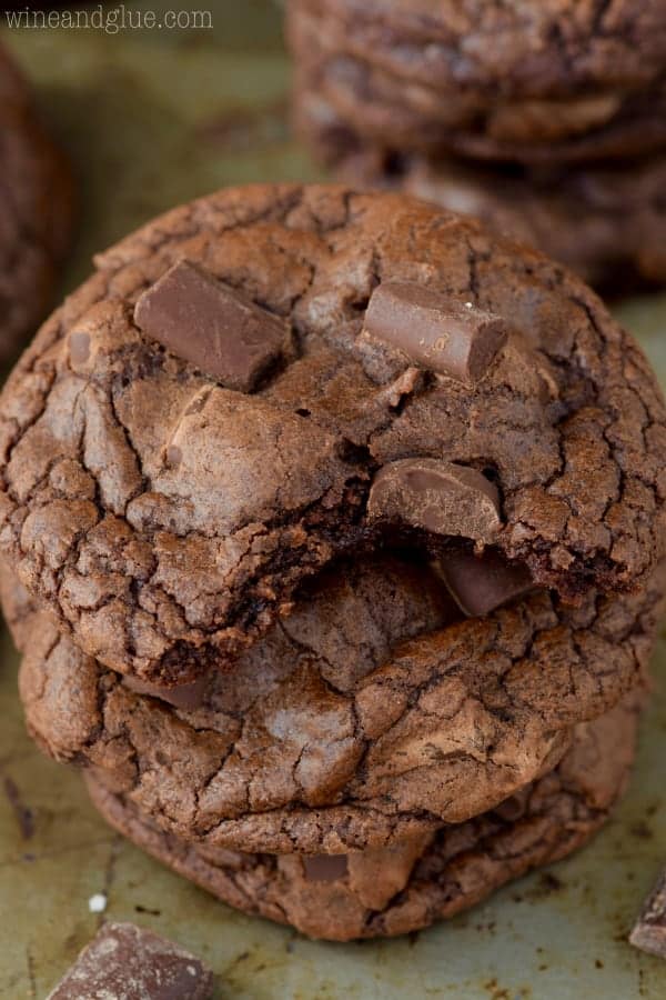 A stack of the Triple Chocolate Chunk Cookies with large chocolate chunks on top and a fluffy interior. 