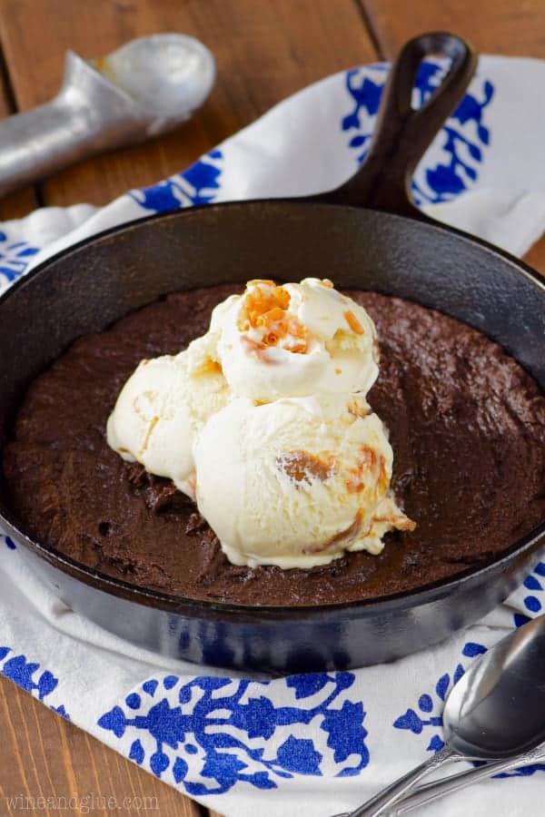 In a cast iron skillet, the Skillet Brownie is fully cooked topped with three caramel gelato scoops. 