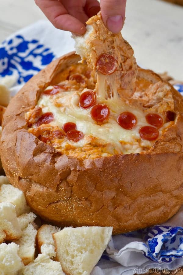 A woman grabbing a piece of bread showing the melted cheese stretch away. 