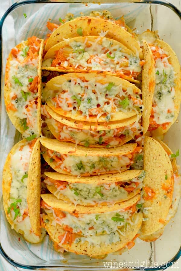 In a glass pan, the Buffalo Baked Tacos are stuffed with Buffalo Chicken topped with melted cheese. 