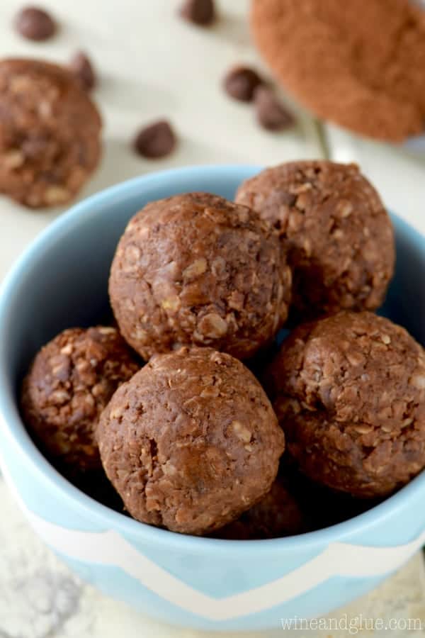 In a blue bowl, the Chocolate Energy Bites are in a sphere shape and has a brown chocolate color. 