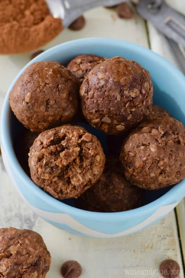 In a blue bowl, the Chocolate Energy Bites are in a sphere shape and has a brown chocolate color. 