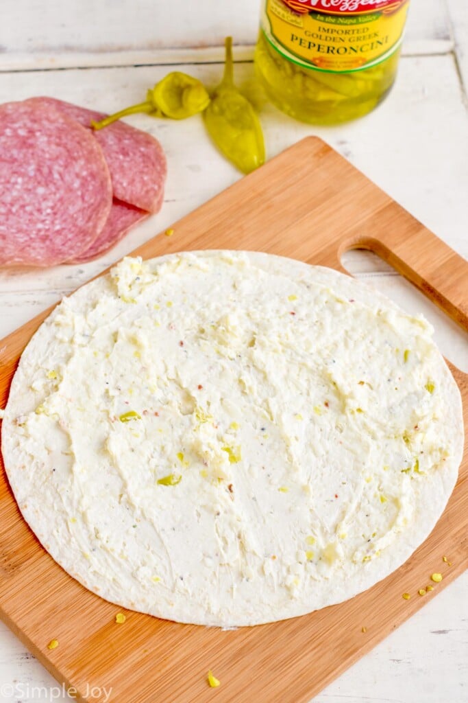 tortilla on a cutting board with a cream cheese mixture spread on it