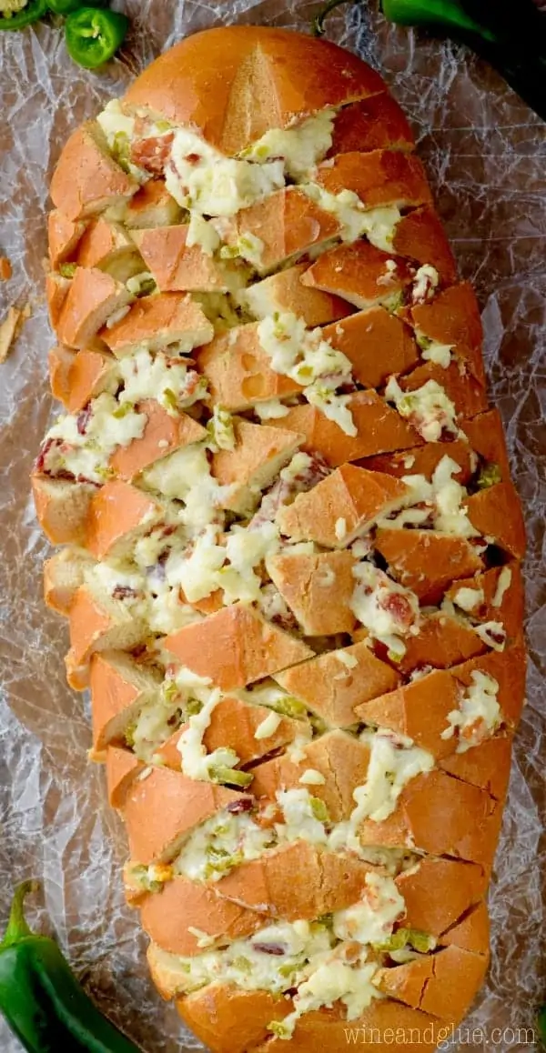 An overhead photo, the Jalapeno Popper Pull Apart Bread is diagonally cut and in the slices melted cheese and minced jalapenos are oozing out. 