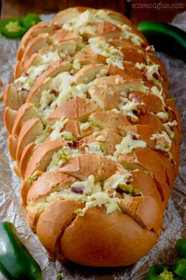 the Jalapeno Popper Pull Apart Bread is diagonally cut and in the slices melted cheese and minced jalapenos are oozing out. 