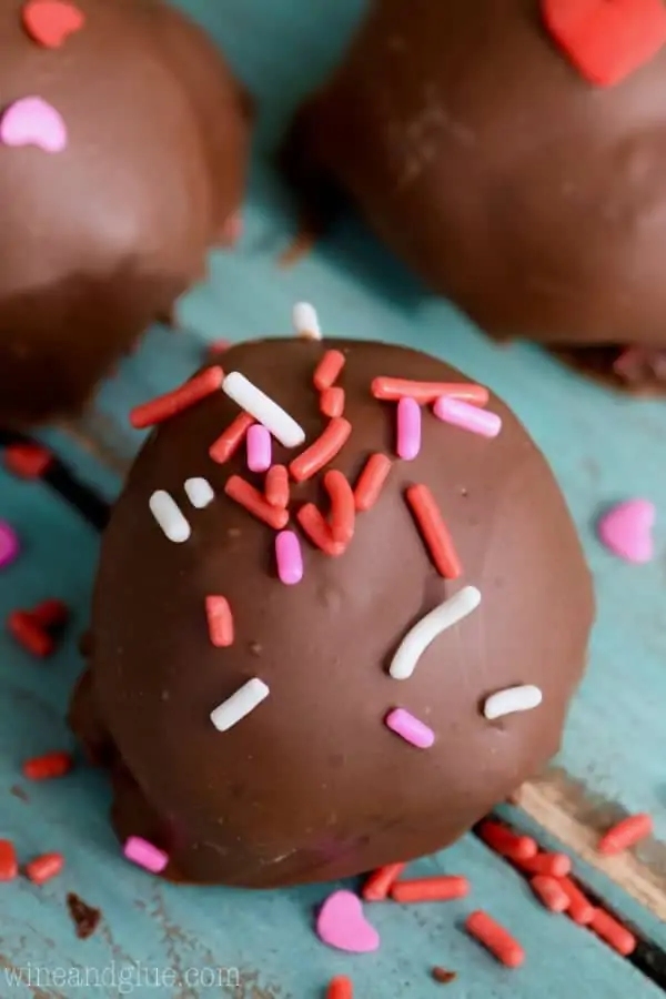 A Red Velvet Chocolate Ganache Truffle topped with red, white, and pink sprinkles. 