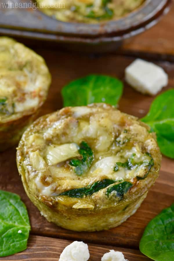 A close up photo of the Spinach and Artichoke Egg Muffin showing the melted feta cheese, spinach, artichoke, and white onion. 