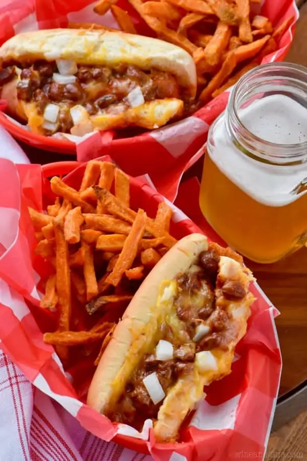 In food baskets, the Oven Baked Chili Cheese Dogs have a side of sweet potato fries and a mason jar full of beer. 