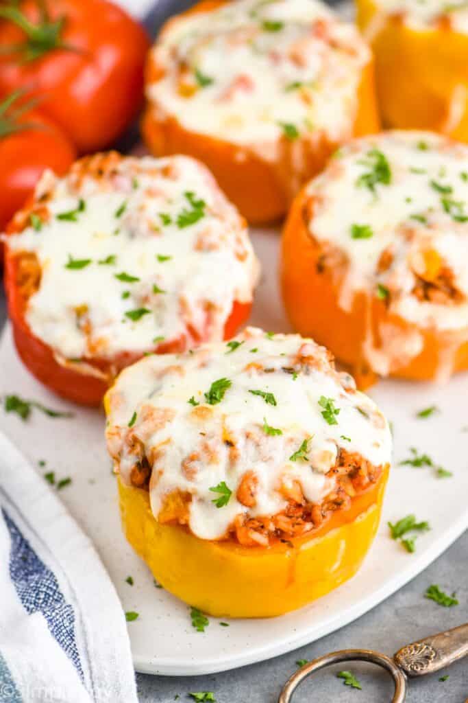 stuffed peppers that are topped with melted mozzarella cheese and garnished with parsley on a platter