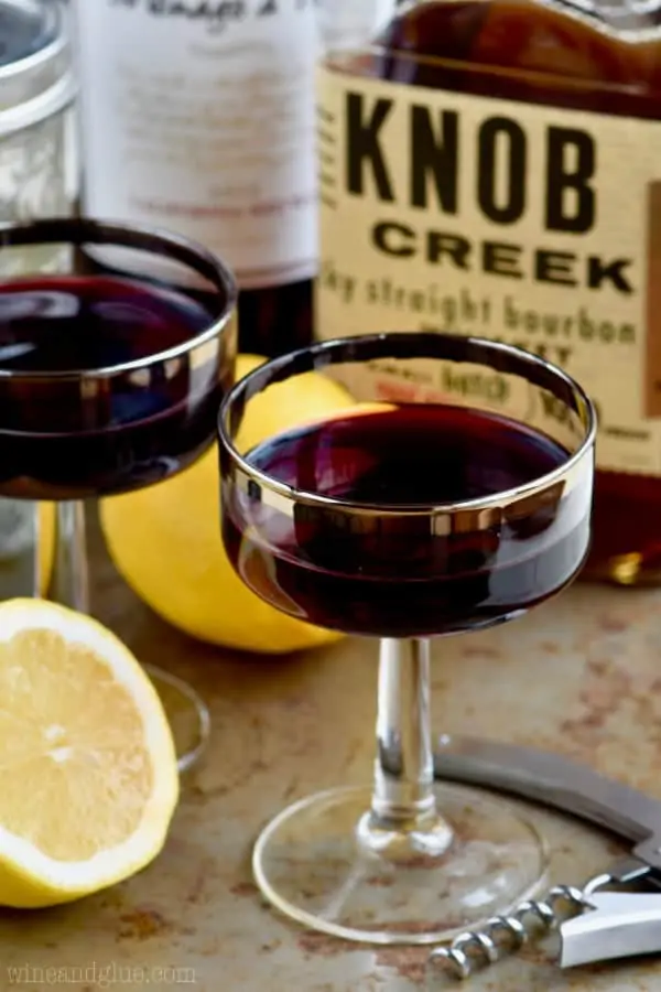 In a long necked glass, the Whiskey and Wine Cocktail has a deep maroon color. 