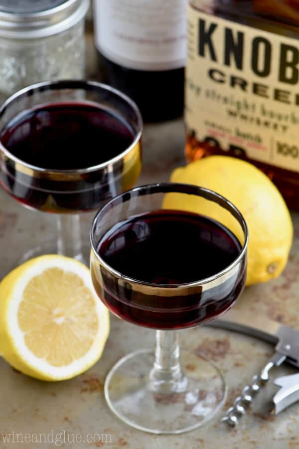 In a long necked glass, the Whiskey and Wine Cocktail has a deep maroon color. 
