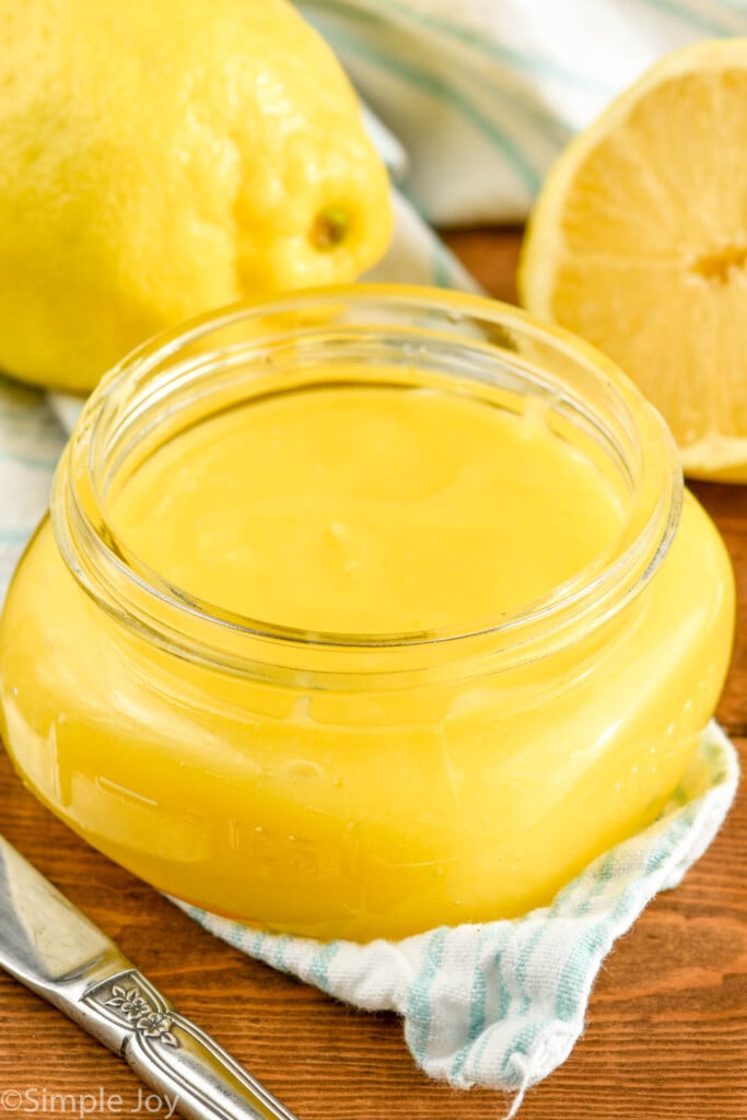 Overhead photo of a jar of Lemon Curd Recipe. Extra lemons in the background.