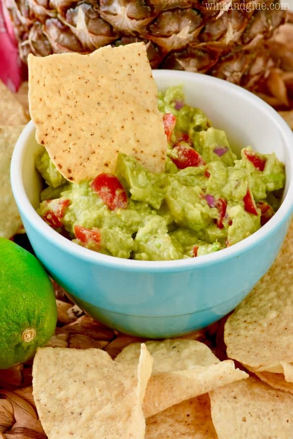 A tortilla chip is being dipped into the Avocado Salsa. 