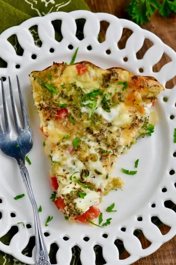 On a white plate, a slice of the Crustless Vegetable Quiche has broccoli, red peppers, cheese, and more peaking out. 