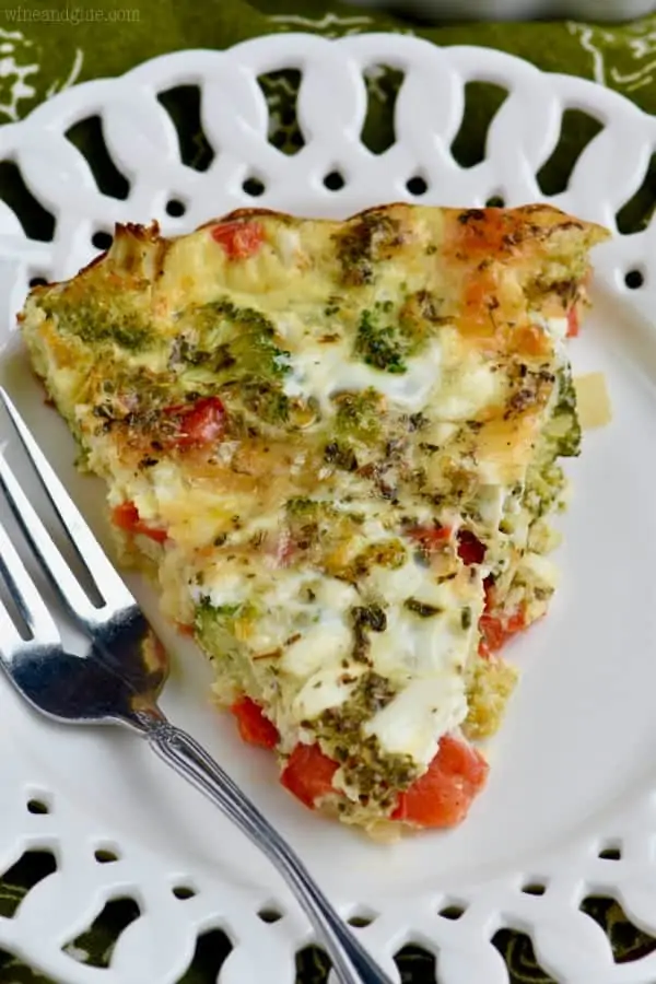 On a white plate, a slice of the Crustless Vegetable Quiche has broccoli, red peppers, cheese, and more peaking out. 