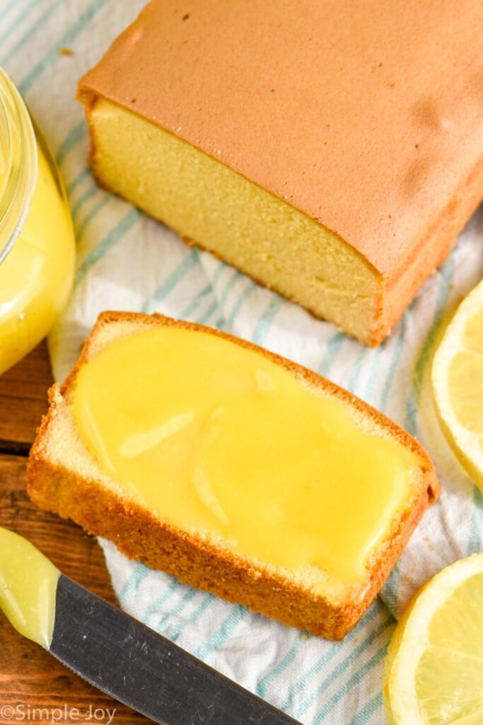 Overhead photo of Lemon Curd Recipe spread onto a slice of bread. Loaf of bread and extra lemons also on counter.