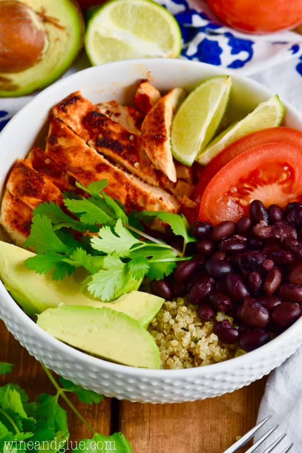 Quinoa taco bowls- Chicken, lime, tomatoes, black beans, avocado quinoa in a bowl garnished with cilantro