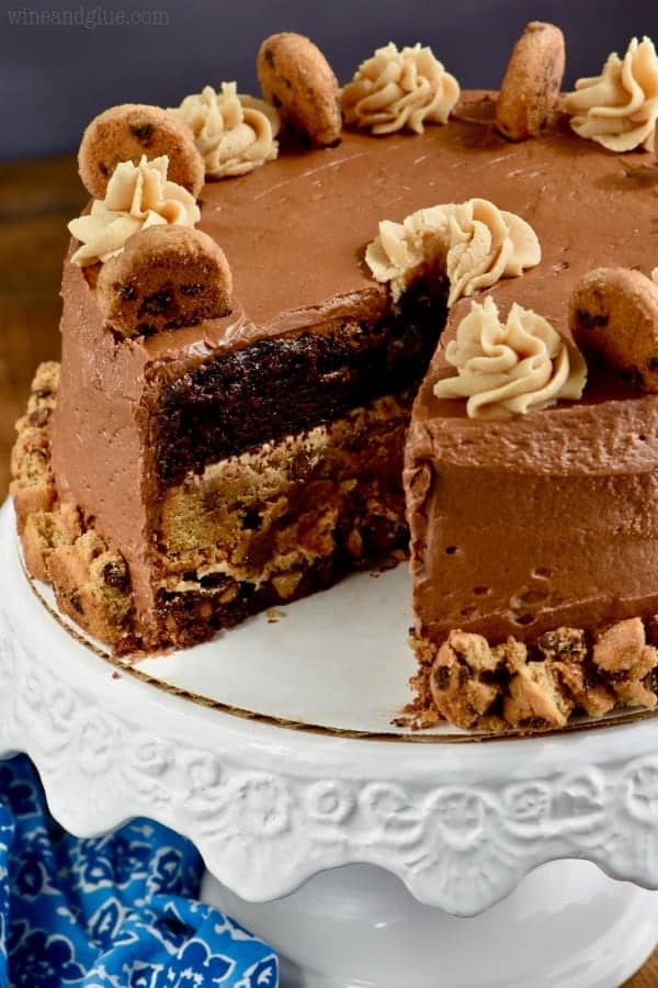 The Chocolate Peanut Butter Cookie Cake has a little slice cut out and topped with chocolate and peanut butter frosting