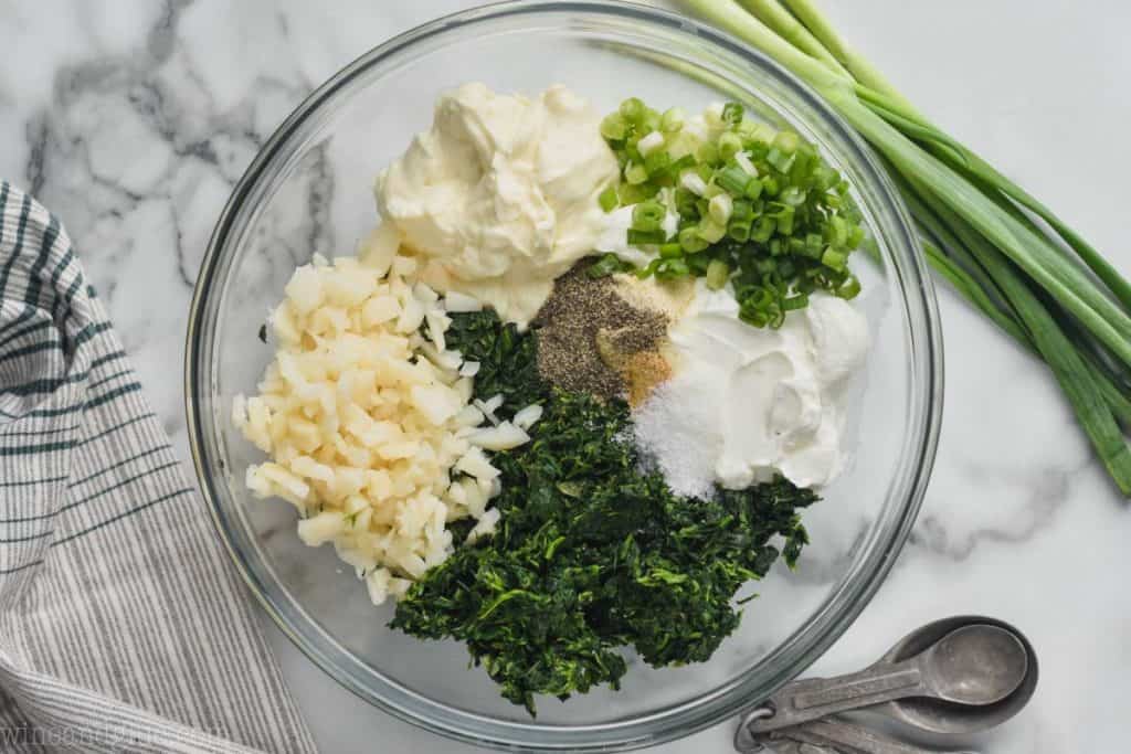 ingredients for easy spinach dip recipe set apart in clear bowl