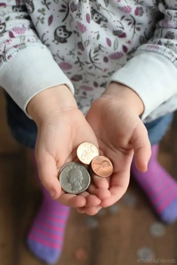 A little girl cupping in her hands some quarters and pennies in her hands. 