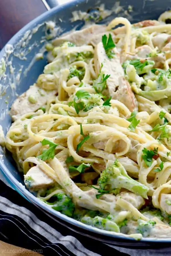 The Lighter Fettuccine Alfredo is a sauce pan and broccoli, chicken pasta, and parsley is mixed in together with a white creamy sauce. 
