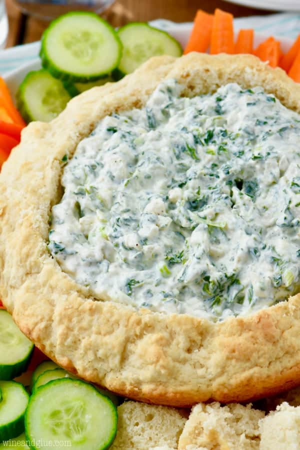 In a little bread bowl, the Spinach Dip is surrounded by carrots, cucumbers, and bell peppers.  