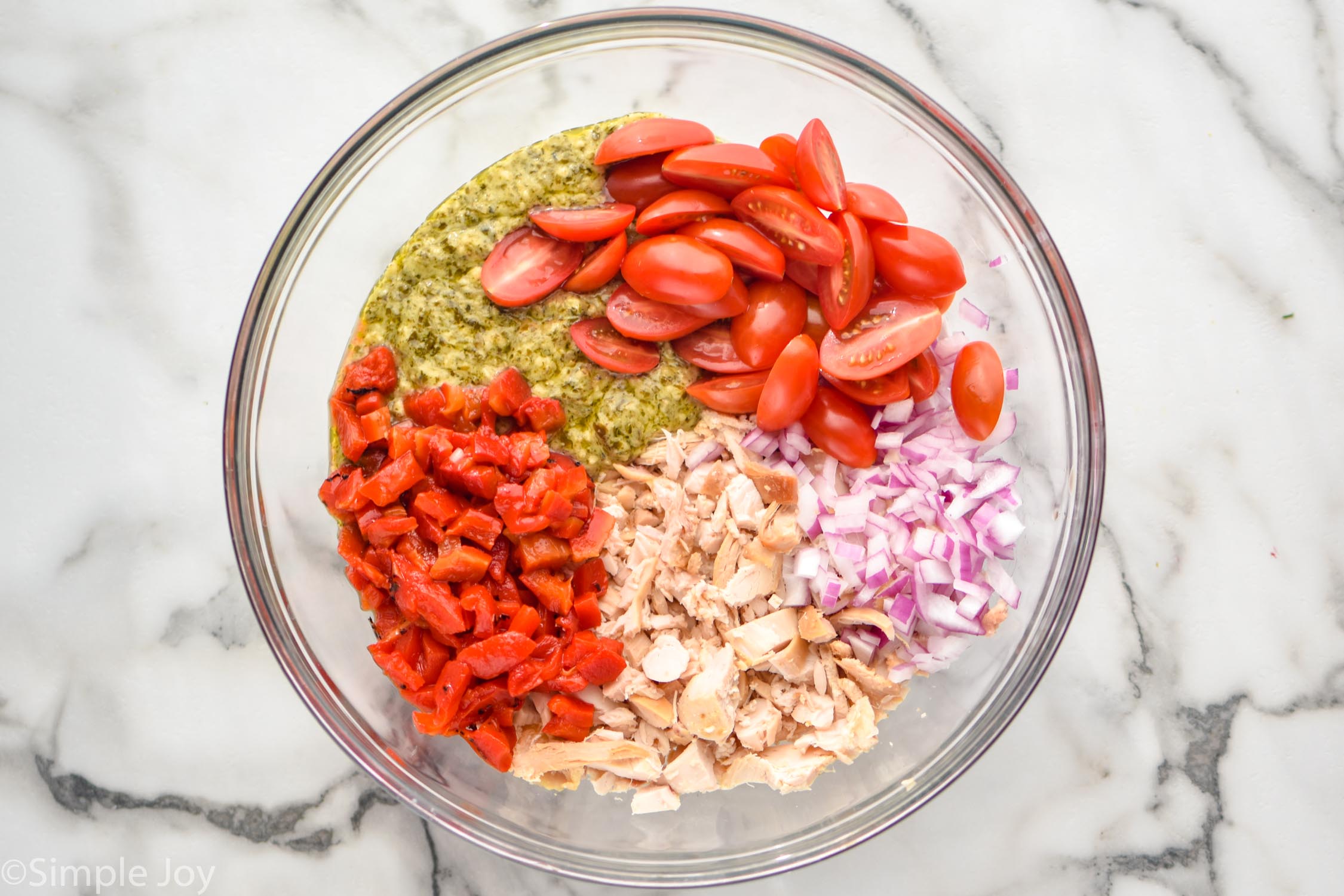 Overhead photo of a mixing bowl of ingredients for Pesto Chicken Salad recipe.