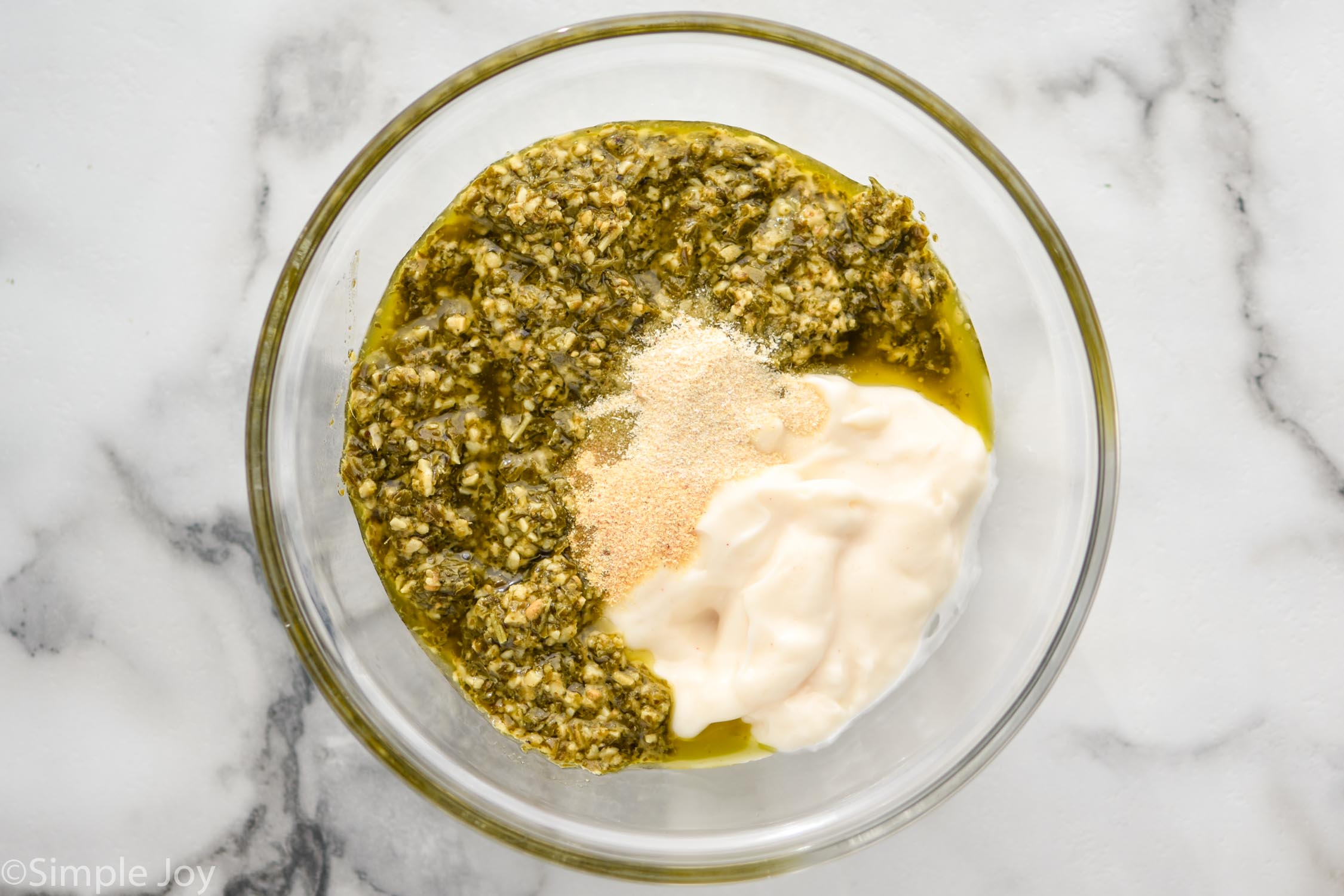 Overhead photo of a mixing bowl of ingredients for Pesto Chicken Salad recipe.